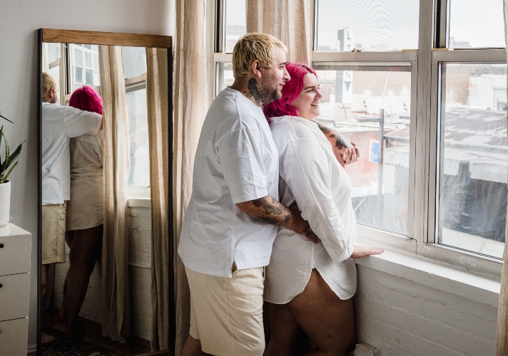 Pareja sonriendo mientras comparte un momento de complicidad, representando que la felicidad en una relación depende del vínculo emocional más que de la apariencia física.